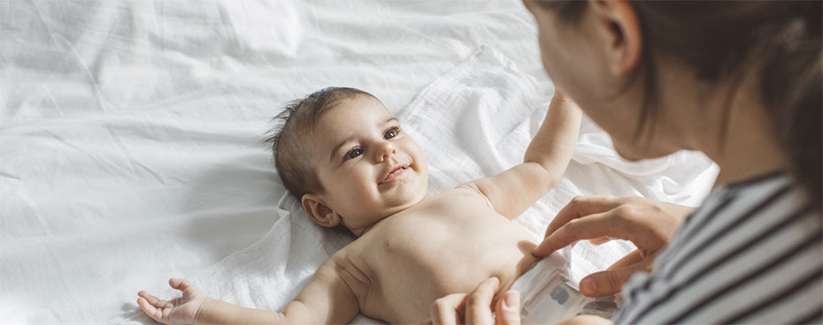 Vrouw verschoont baby op bed. Vrouw verschoont baby op bed.