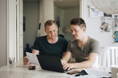 Twee mannen doen administratie achter laptop