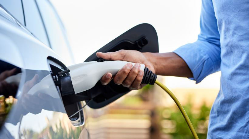 Een persoon die een elektrische auto oplaadt