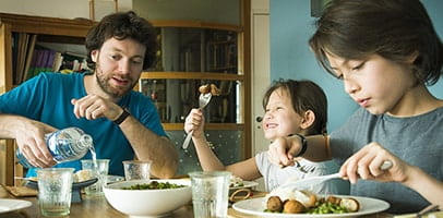 gezin vader met kinderen eten aan tafel