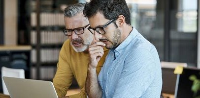 Een man en vrouw zitten samen achter een computer en kijken op een scherm