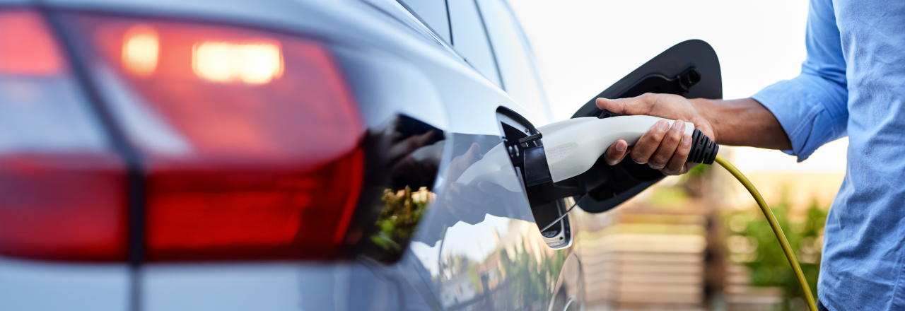 Een persoon die een elektrische auto oplaadt