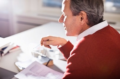 man zit met documenten aan bureau