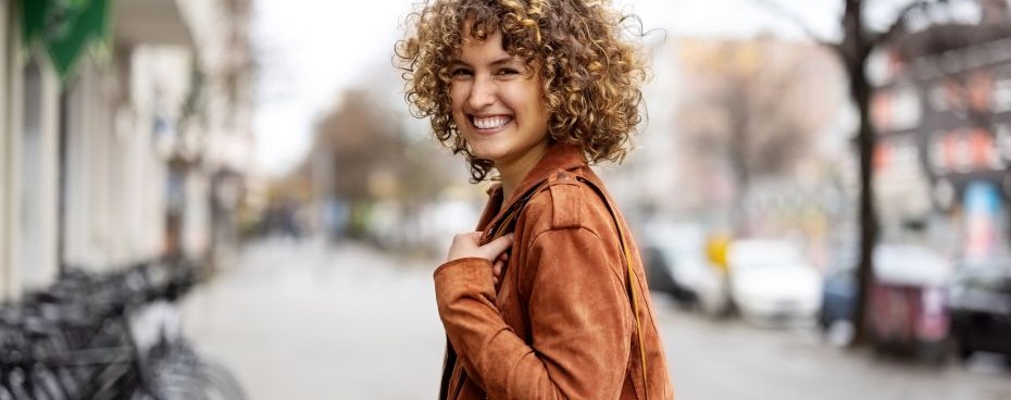 Een vrouw die buiten loopt met op de achtergrond fietsen.” in een stedelijke straat met op de achtergrond fietsen