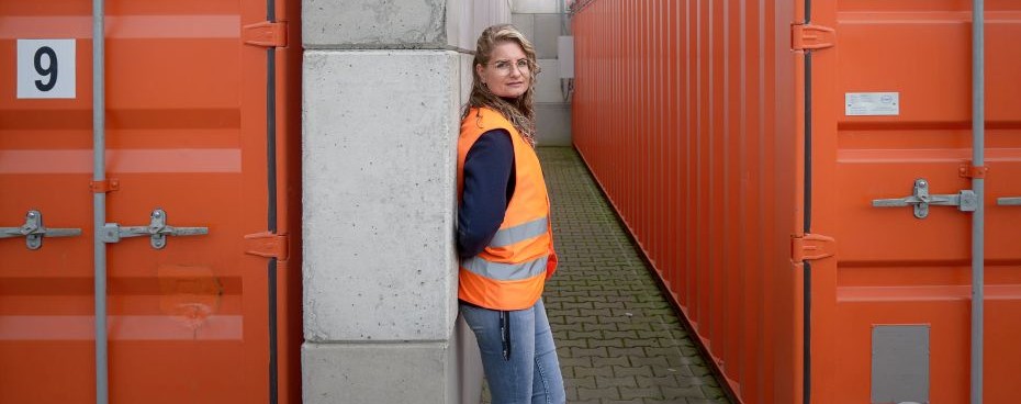 Een vrouw met veiligheidshesje staat voor de opslag van lithium-ion accu's in haar bedrijf