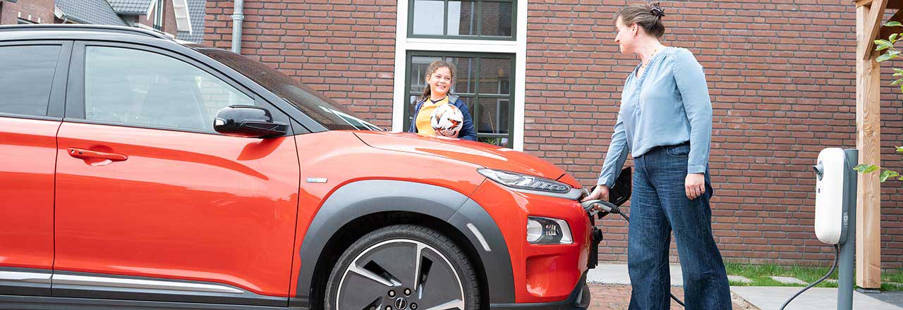 Vrouw met dochter laadt elektrische auto op