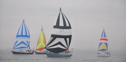 Een afbeelding van 3 zeilboten op het water. De boten hebben kleurrijke zeilen