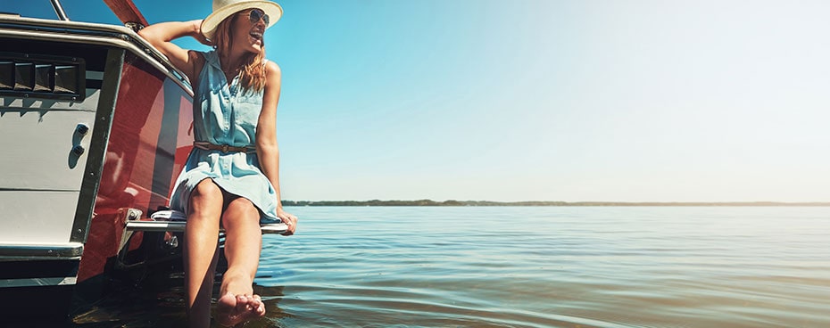 Lachende jonge vrouw op boot geniet van haar financiële onafhankelijkheid.