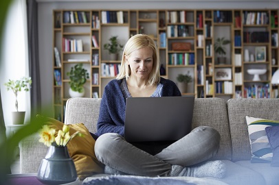 Vrouw zit op de bank met laptop op schoot